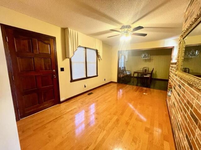 foyer featuring ceiling fan, wood-type flooring, and a textured ceiling