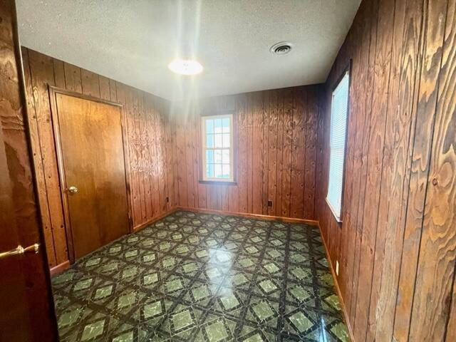 spare room featuring a textured ceiling and wood walls