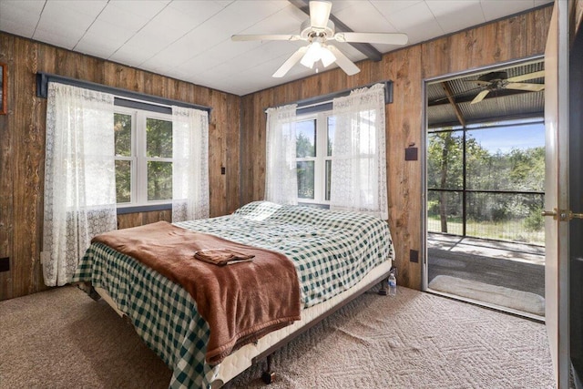 bedroom featuring wooden walls, carpet flooring, a ceiling fan, and access to exterior