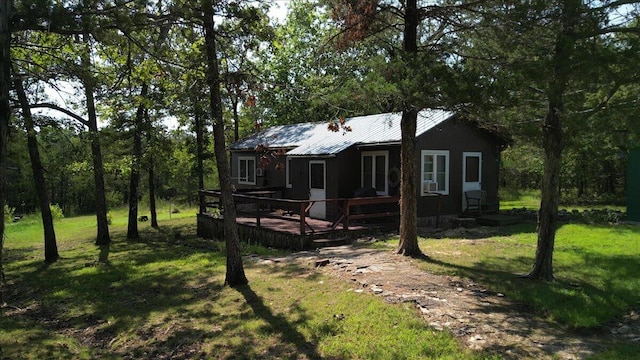 back of house with a wooden deck, a yard, and metal roof