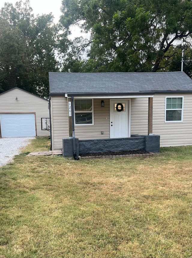 view of front facade featuring a garage, a front yard, and an outbuilding