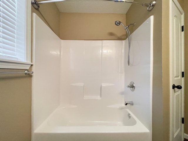 bathroom featuring washtub / shower combination and a textured ceiling