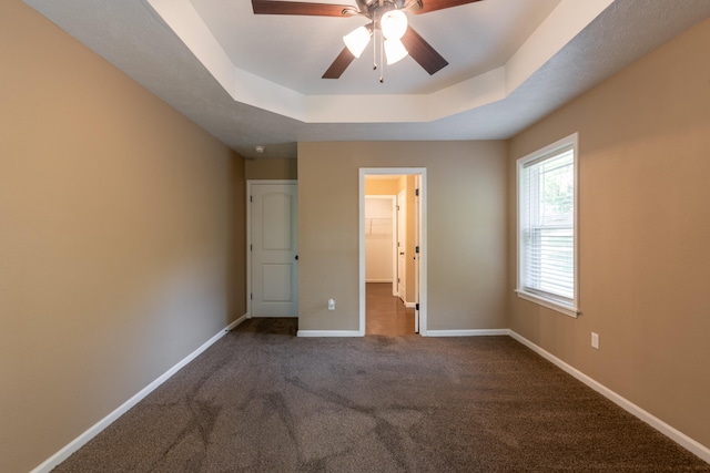 unfurnished bedroom featuring ceiling fan, a tray ceiling, and carpet