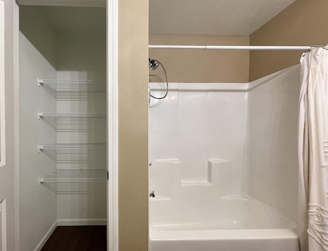 bathroom with shower / bath combo with shower curtain and a textured ceiling