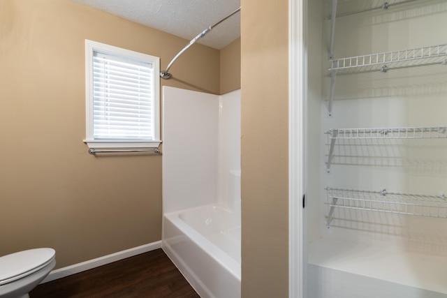 bathroom with shower / tub combination, toilet, wood-type flooring, and a textured ceiling