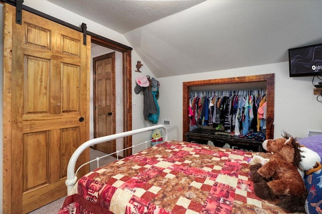 bedroom featuring a barn door, lofted ceiling, a textured ceiling, and carpet