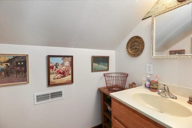 bathroom featuring lofted ceiling, vanity, and a textured ceiling