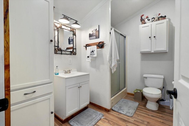 bathroom with a shower stall, toilet, crown molding, and wood finished floors