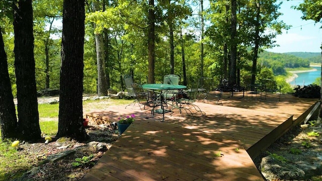 view of community featuring a deck with water view and outdoor dining area