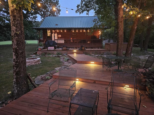 wooden deck featuring a fire pit, a lawn, outdoor dining area, and a grill
