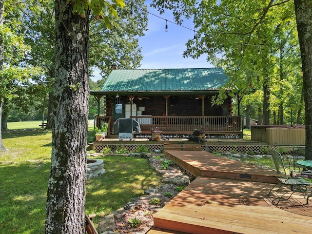 exterior space with a deck, a hot tub, a yard, metal roof, and log exterior
