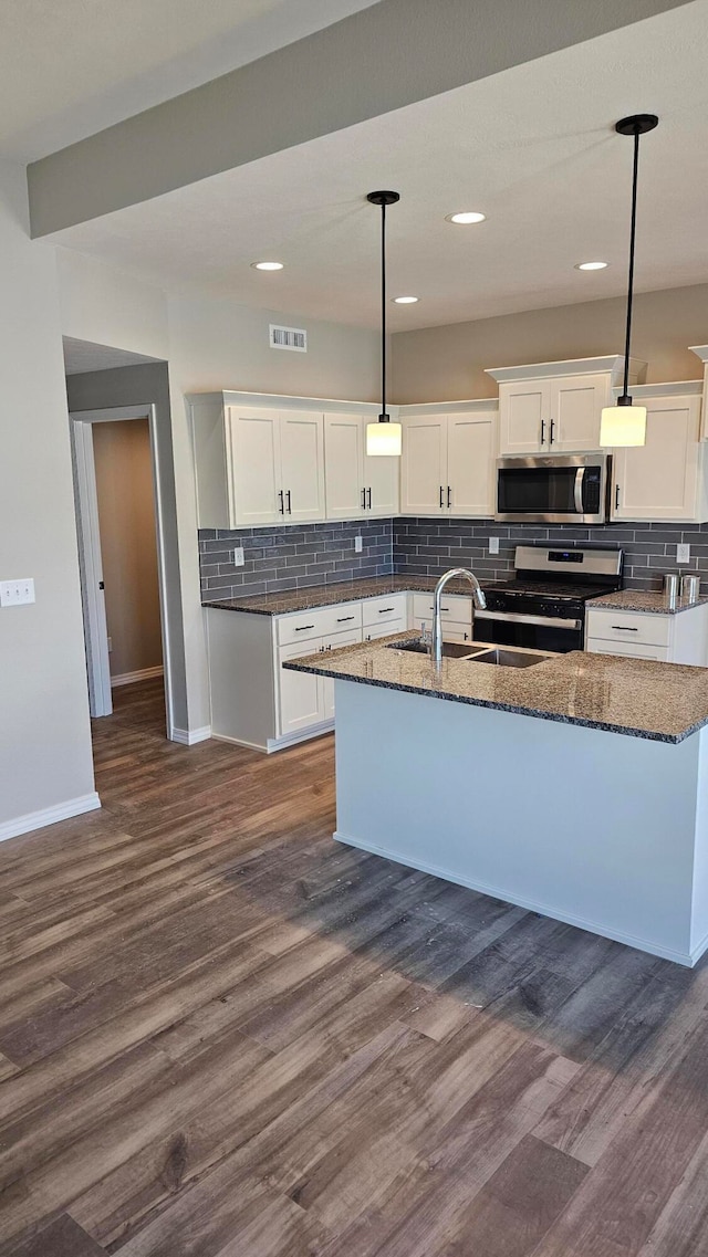 kitchen with white cabinets, pendant lighting, appliances with stainless steel finishes, dark hardwood / wood-style floors, and decorative backsplash