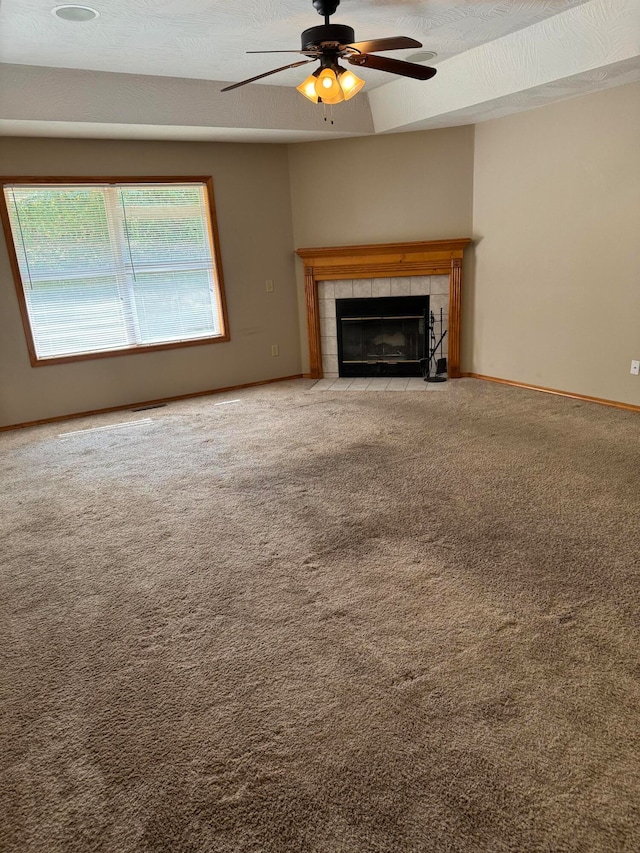 unfurnished living room with ceiling fan, a textured ceiling, carpet flooring, and a tile fireplace