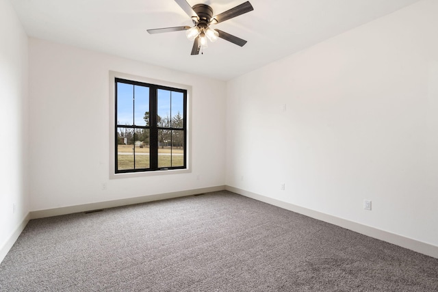 carpeted spare room featuring ceiling fan and baseboards