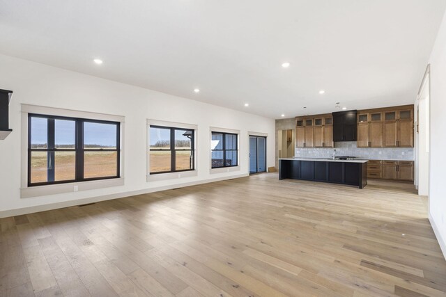 kitchen featuring tasteful backsplash, open floor plan, light countertops, and light wood finished floors