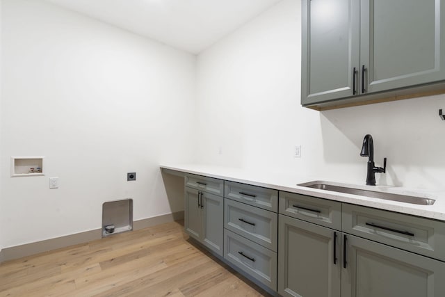 laundry area with light wood finished floors, hookup for a washing machine, cabinet space, hookup for an electric dryer, and a sink