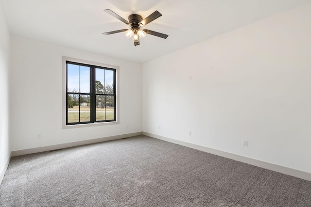 carpeted spare room featuring a ceiling fan and baseboards