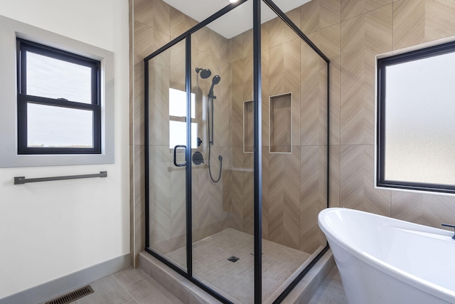 full bathroom with visible vents, baseboards, tile patterned floors, a freestanding tub, and a shower stall