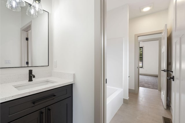 bathroom with a bathtub, visible vents, baseboards, and vanity