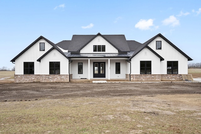 modern inspired farmhouse with metal roof, covered porch, brick siding, board and batten siding, and a standing seam roof