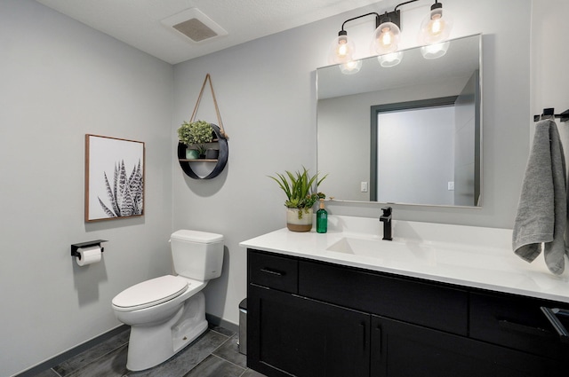 bathroom featuring vanity, tile patterned flooring, toilet, and a textured ceiling