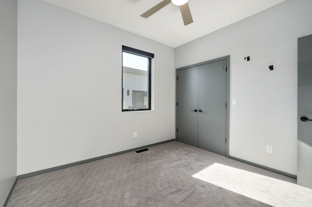 unfurnished bedroom with ceiling fan, light colored carpet, and a closet