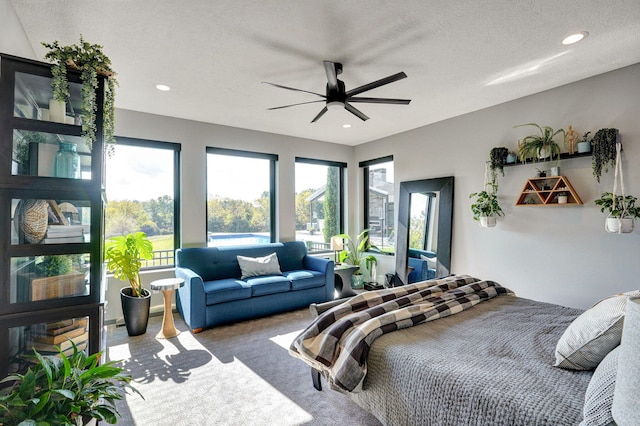 carpeted bedroom with ceiling fan and a textured ceiling