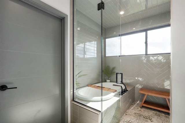 bathroom with a relaxing tiled tub and tile walls