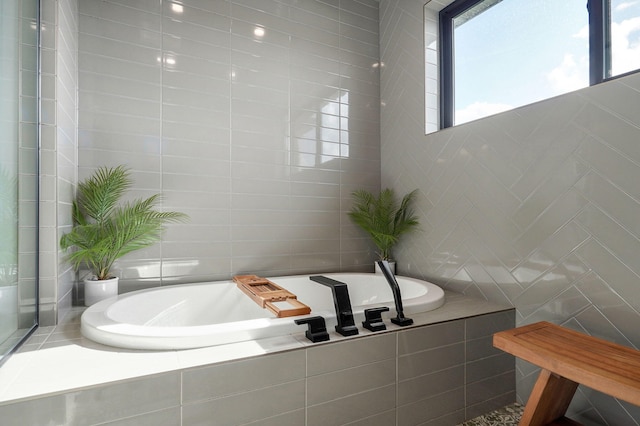 bathroom with a relaxing tiled tub and tile walls