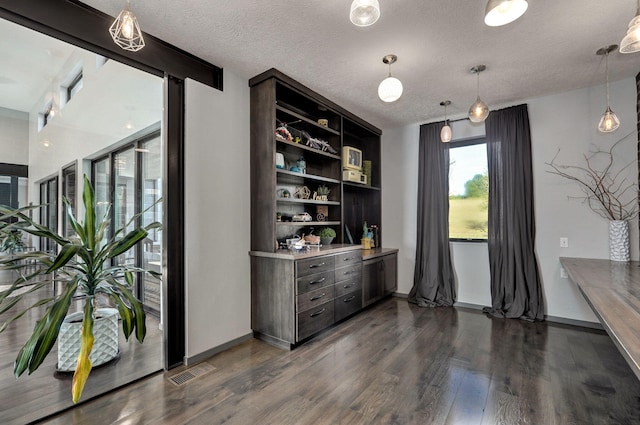 bar featuring dark brown cabinetry, dark hardwood / wood-style floors, and a textured ceiling