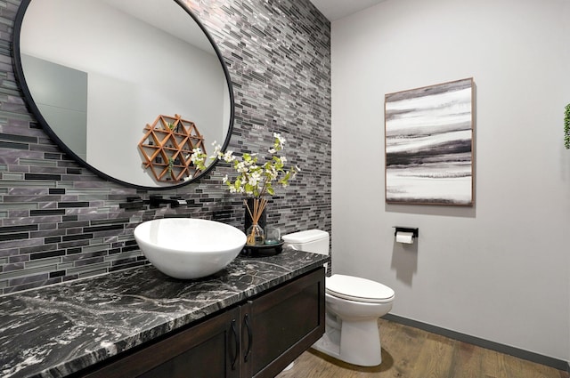 bathroom with backsplash, hardwood / wood-style flooring, vanity, and toilet