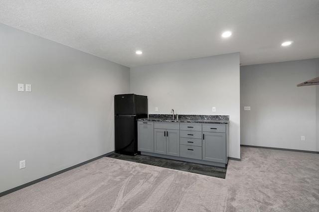 kitchen with dark carpet, sink, a textured ceiling, gray cabinets, and black refrigerator