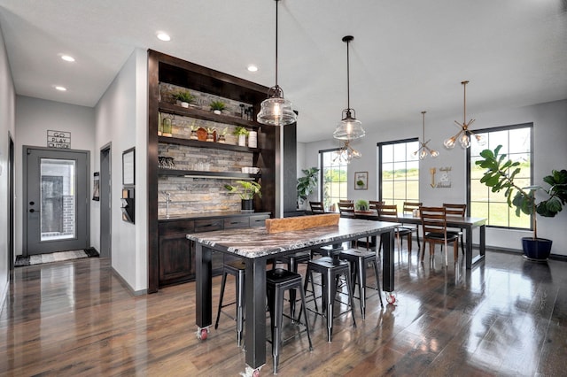 kitchen with pendant lighting, plenty of natural light, a breakfast bar, and dark brown cabinets