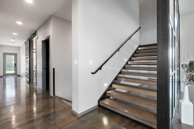 staircase featuring a barn door and hardwood / wood-style floors