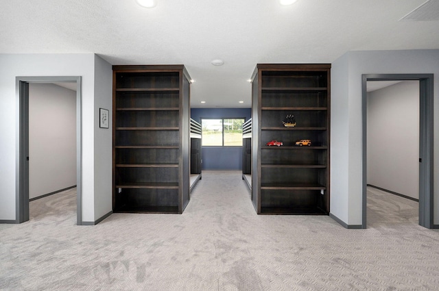 hall featuring a textured ceiling and light colored carpet