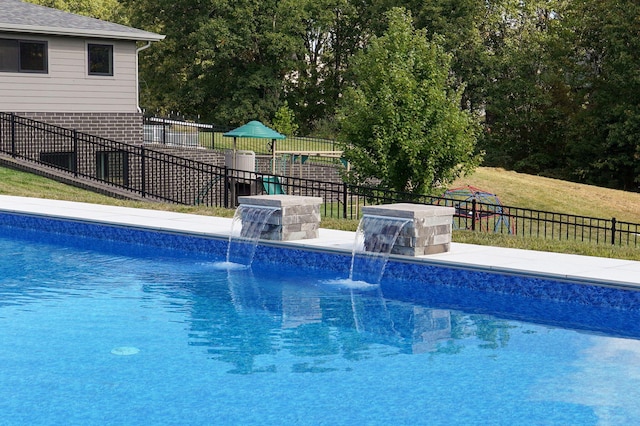 view of pool with a yard and pool water feature