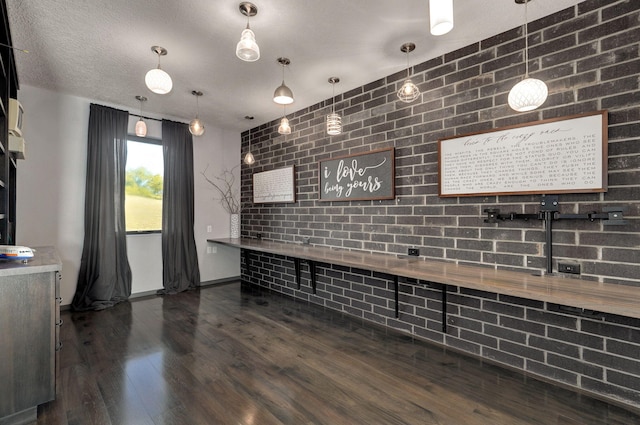 kitchen featuring brick wall, pendant lighting, a textured ceiling, and dark hardwood / wood-style floors