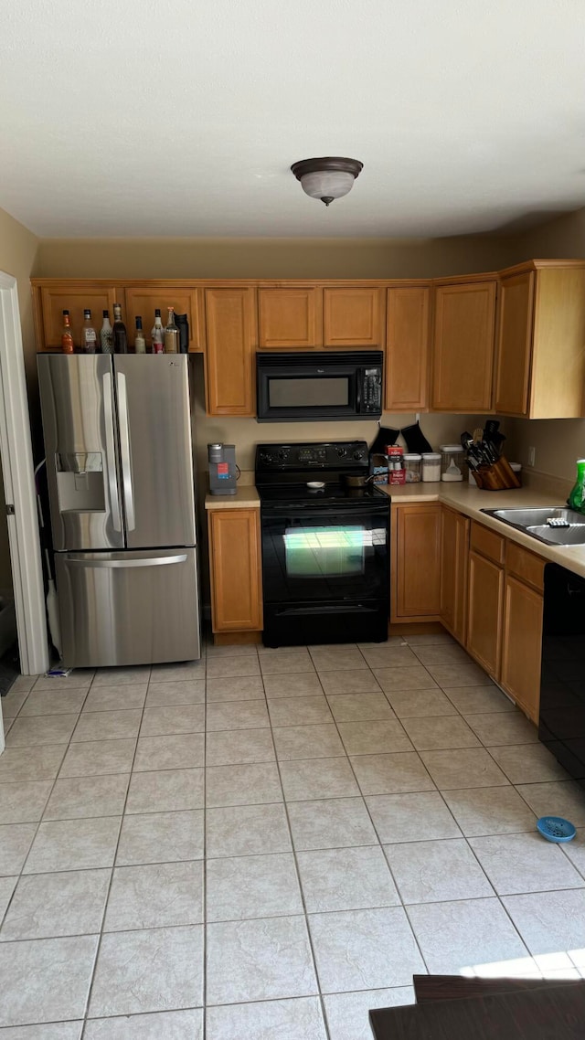 kitchen with light tile patterned flooring, black appliances, and sink