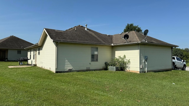 rear view of house with central AC and a lawn