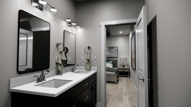 full bath featuring connected bathroom, wood finished floors, a sink, and double vanity