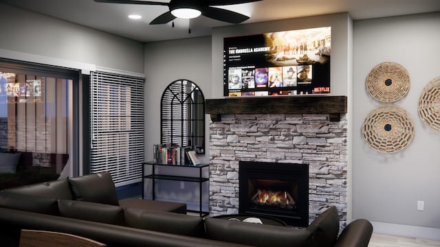 living area with recessed lighting, a stone fireplace, wood finished floors, a ceiling fan, and baseboards