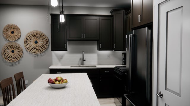 kitchen featuring light countertops, backsplash, a sink, decorative light fixtures, and black appliances