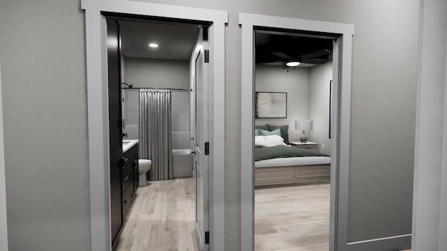ensuite bathroom with wood finished floors, toilet, vanity, shower / tub combo with curtain, and ensuite bath