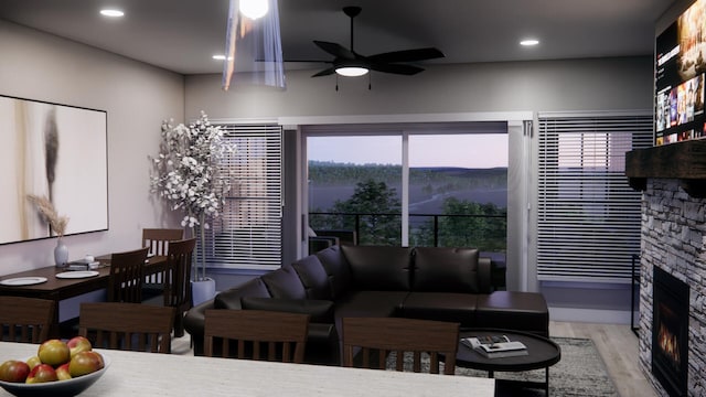 living room with ceiling fan, a stone fireplace, and light wood-type flooring