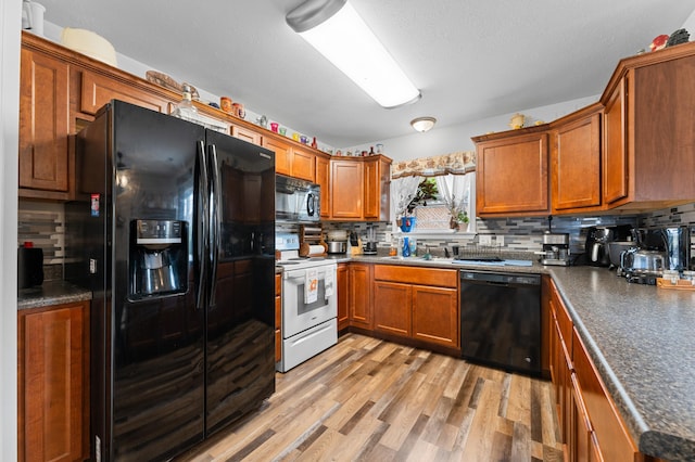 kitchen with black appliances, sink, light hardwood / wood-style floors, and tasteful backsplash