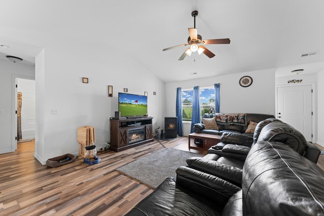 living room featuring a fireplace, ceiling fan, vaulted ceiling, and wood-type flooring