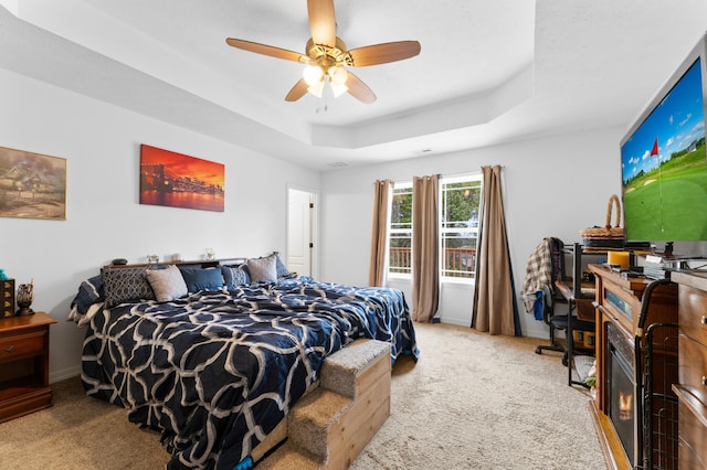 carpeted bedroom featuring ceiling fan and a tray ceiling