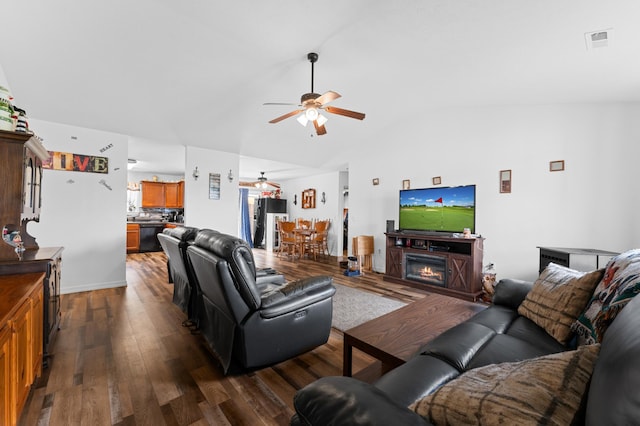 living room featuring ceiling fan, dark hardwood / wood-style floors, and vaulted ceiling