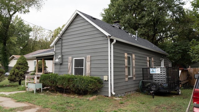 view of home's exterior featuring roof with shingles and fence