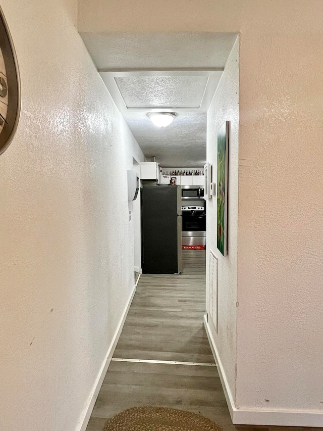 corridor featuring a textured ceiling and hardwood / wood-style flooring